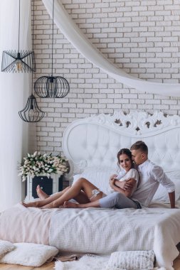 Birbirine aşık genç bir çiftin portresi. Yatakta sarılıyorlar.                