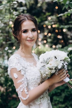 Beyaz elbiseli güzel gelin elinde düğün buketi                 