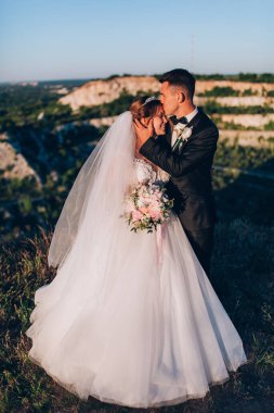 Gelin ve damat doğada düğün gününde poz veriyorlar. Birbirine aşık çift..