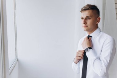 Beyaz gömlekli ve siyah kravatlı yakışıklı bir adamın portresi.