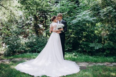 Güzel, mutlu, genç bir çift yeşil parkta birbirlerine poz veriyorlar.              