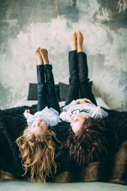 Stüdyo odasında yatakta poz veren genç mutlu anne ve kız. 