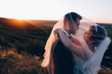 Genç ve mutlu bir çiftin akşamları dışarıda kucaklaşmasının yan görüntüsü.