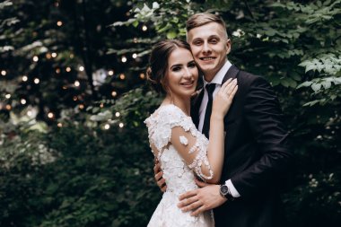 Güzel, mutlu, genç bir çift yeşil parkta birbirlerine poz veriyorlar.              