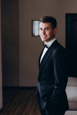 Yakışıklı genç damat portresi. Düğün gününde şık siyah takım elbise ve papyon takıyor.        