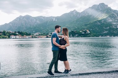 Genç çift, arka planda, dağlarda ve manzaralı gölde sarılıyor. 