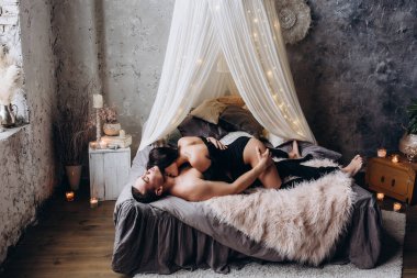 Mutlu romantik çift yatakta uzanıp öpüşüyor.