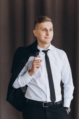Siyah takım elbiseli ve beyaz gömlekli yakışıklı genç adamın portresi yana bakıyor.