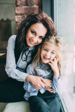 Anne ve kızı modern stüdyo içinde poz veriyorlar. 