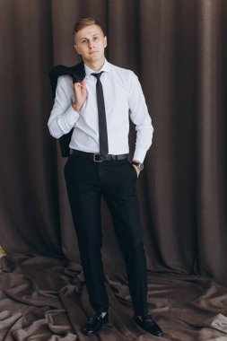 Siyah takım elbiseli, beyaz gömlekli ve kameraya bakan yakışıklı bir gencin portresi. 