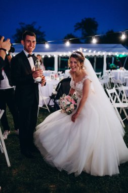 Güzel, mutlu, genç bir düğün çifti geceleri dışarıda gülüyor.