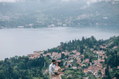 Mutlu gelin ve damat dağ gölü kıyısında yürüyorlar.                