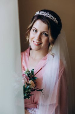 Pembe ipek bornoz ve duvak içinde güzel bir gelin Sabah düğün buketi tutuyor            