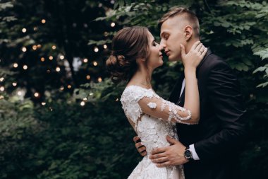 Güzel, mutlu, genç bir çift yeşil parkta birbirlerine poz veriyorlar.              