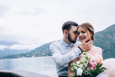 Güzel bir düğün çifti, gelin ve damat göl kenarında kucaklaşıyorlar. 