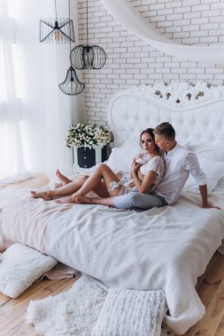 Birbirine aşık genç bir çiftin portresi. Yatakta sarılıyorlar.                