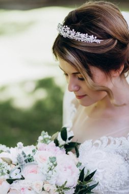 Gelinlikli güzel gelinin portresi Parkta bir buket çiçek tutuyor            