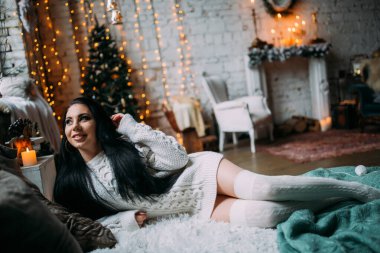 Güzel, genç, esmer bir kadın, rahat bir şekilde yatakta uzanıyor.                       