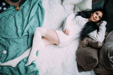 Güzel, genç, esmer bir kadın, rahat bir şekilde yatakta uzanıyor.                       