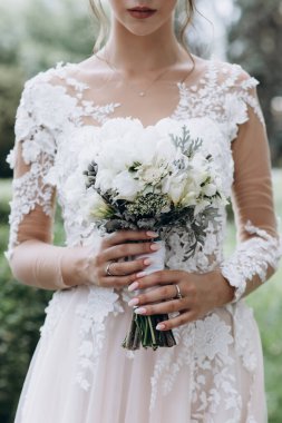 Beyaz elbiseli genç gelinin elinde bir buket düğün fotoğrafı.