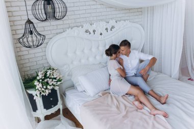 Birbirine aşık genç bir çiftin portresi. Yatakta sarılıyorlar.                