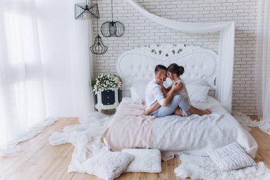 Birbirine aşık genç bir çiftin portresi. Yatakta sarılıyorlar.                