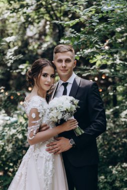 Güzel, mutlu, genç bir çift yeşil parkta birbirlerine poz veriyorlar.              