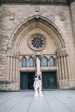 Güzel gelin ve damat düğün gününde katedralin yanında poz veriyor.