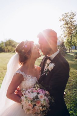 Güzel mutlu gelin ve damat doğada gün batımında poz veriyor.                