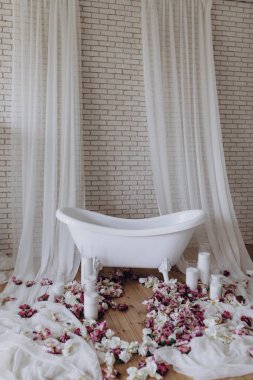 Banyoda çiçek yaprakları ve mumlarla dolu beyaz bir banyo.