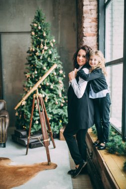 Anne ve kızı stüdyoda Noel ağacıyla poz veriyorlar.