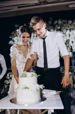 Mutlu gelin ve damat güzel bir düğün pastası kesiyor. 