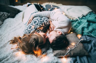 Genç ve mutlu bir çift yerde yatıyor. Stüdyoda Noel dekoru ile poz veriyor.