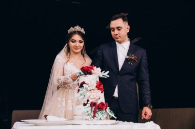 Mutlu gelin ve damat restoranda düğün pastası kesiyor.