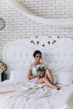 Beyaz dantelli iç çamaşırlı güzel bir kadın ve sabah yatak odasında bir buket düğün çiçeği.              