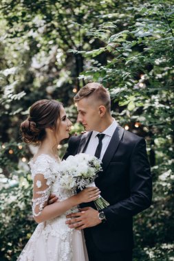 Güzel, mutlu, genç bir çift yeşil parkta birbirlerine poz veriyorlar.              