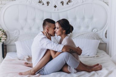 Birbirine aşık genç bir çiftin portresi. Yatakta sarılıyorlar.                