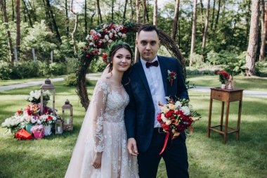 Güzel, mutlu, genç gelin ve damat açık havada evleniyor.