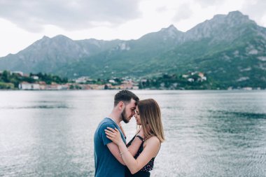 Birbirlerine aşık güzel bir çift. Manzaralı dağ gölü kenarında kucaklaşıyorlar.       