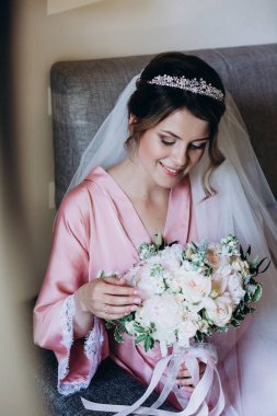 Pembe ipek bornoz ve duvak içinde güzel bir gelin Sabah düğün buketi tutuyor            
