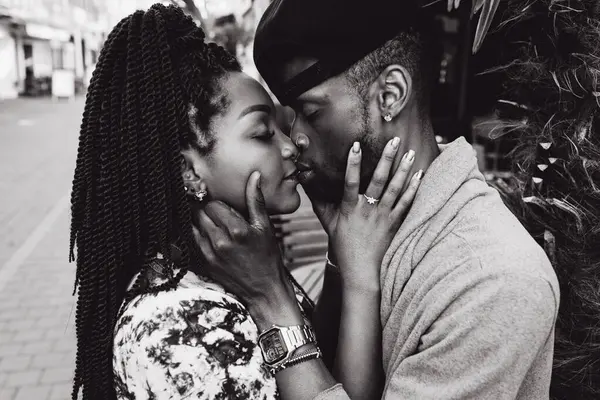 Afrikalı çift sokakta öpüşüyor ve sarılıyor.