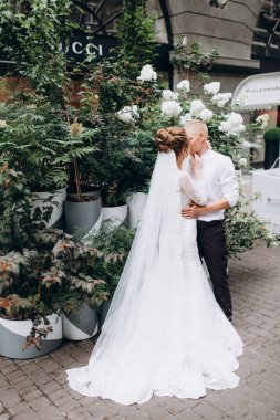 Güzel gelin ve damat şehirde öpüşüyor ve kucaklaşıyor.