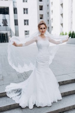 Şehirde poz veren zarif beyaz gelinlik içindeki güzel genç gelinin portresi.          