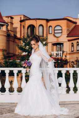 Şehirde poz veren zarif beyaz gelinlik içindeki güzel genç gelinin portresi.          