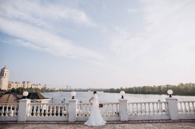 Köprüde durup nehire bakan genç gelinin arka manzarası