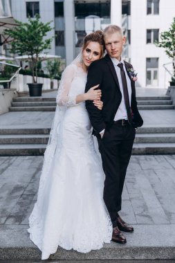 Güzel mutlu gelin ve damat şehirde yürüyor.         