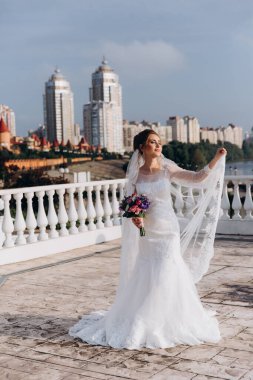 Şehirde poz veren zarif beyaz gelinlik içindeki güzel genç gelinin portresi.          