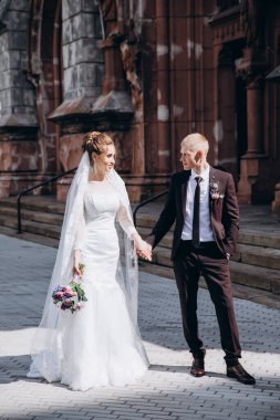 Güzel mutlu gelin ve damat şehirde yürüyor.         