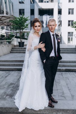 Güzel bir çift mutlu gelin ve damat şehirde birlikte poz veriyorlar.               