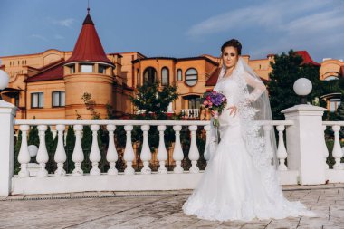 Şehirde poz veren zarif beyaz gelinlik içindeki güzel genç gelinin portresi.          